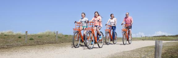 Family cycling in Holland by the beach